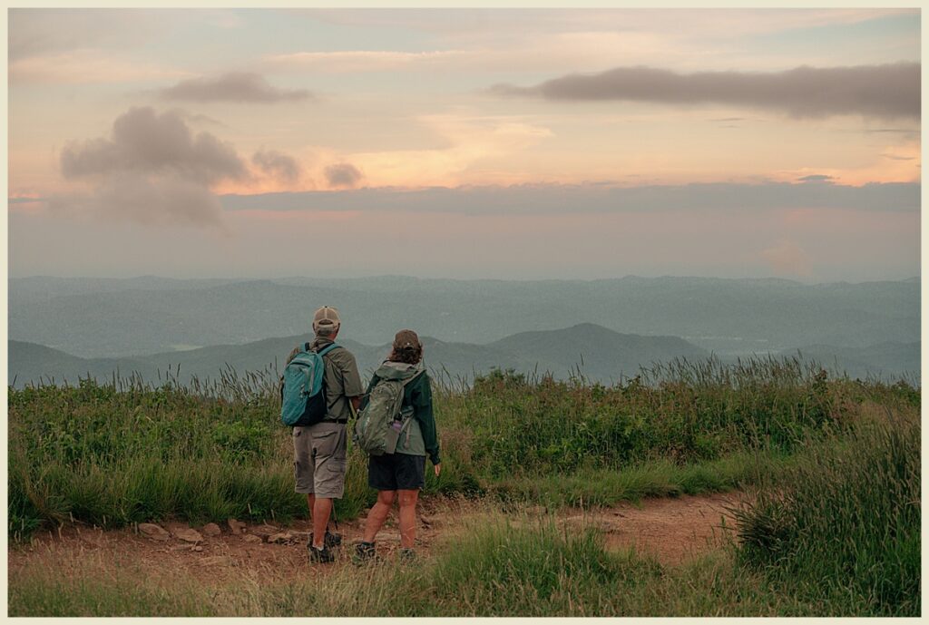 Travel Photography in Asheville, NC featuring a couple hiking Black Balsam Knob at a moody sunset.